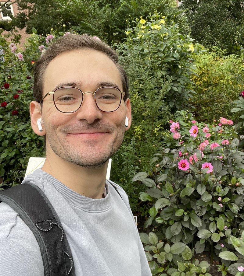 Ryan smiling among flowering garden plants